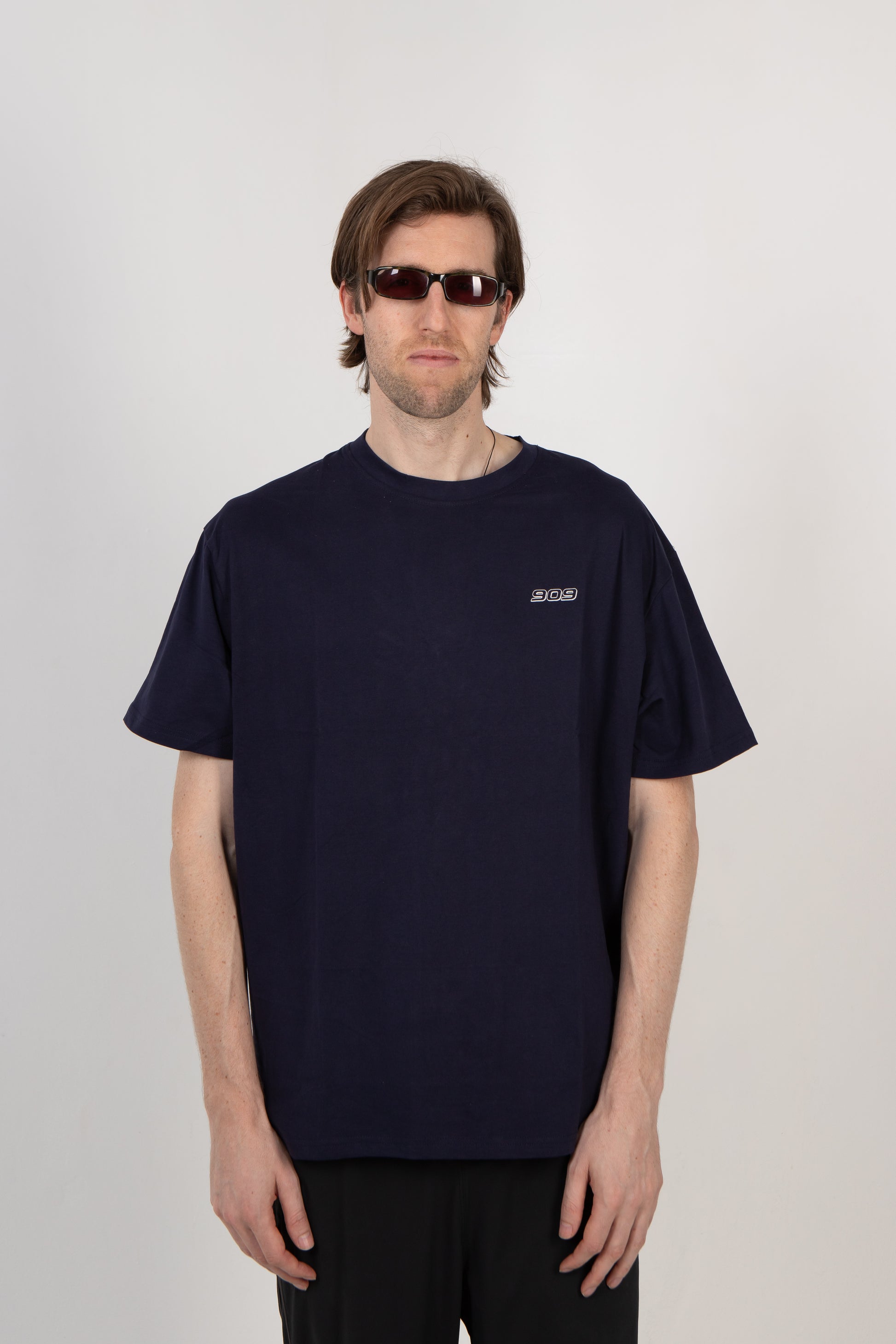 Man wearing a navy blue t-shirt with a logo on a plain background