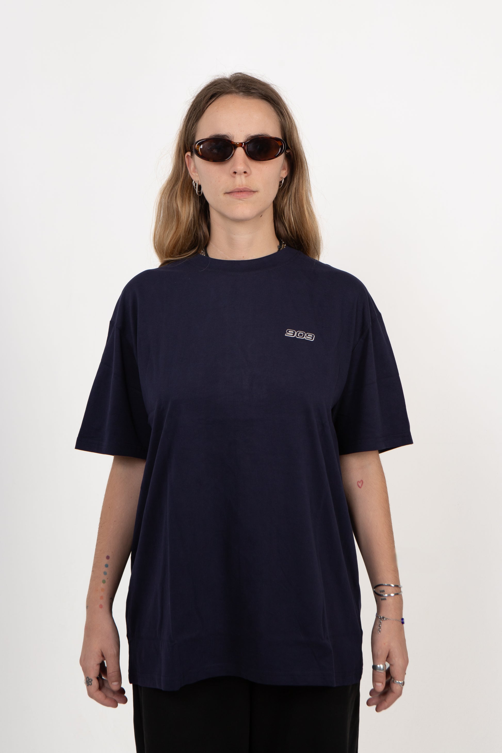 Person wearing a navy blue t-shirt with a small logo on a white background