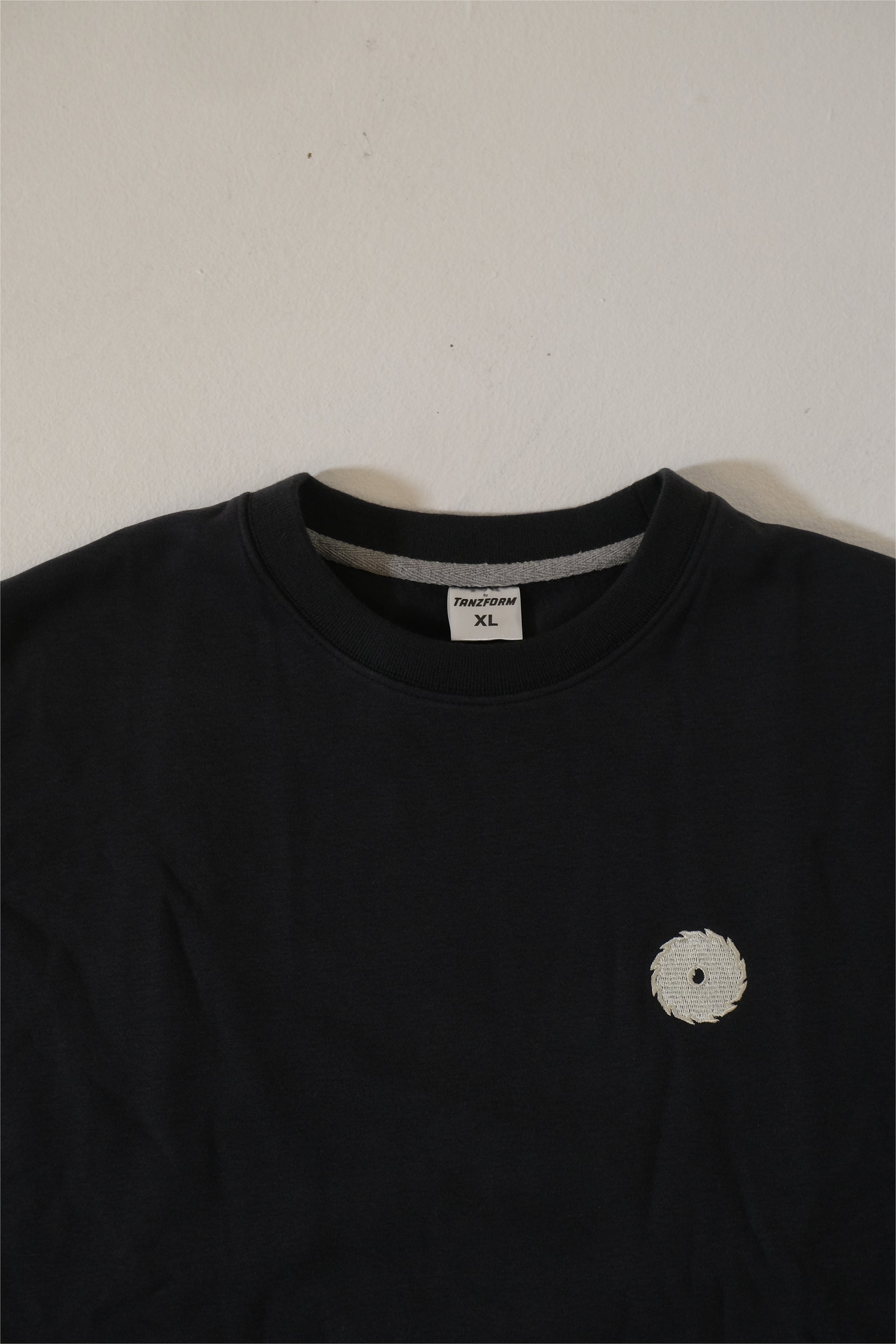 Navy sweatshirt with a small white logo on a light gray background
