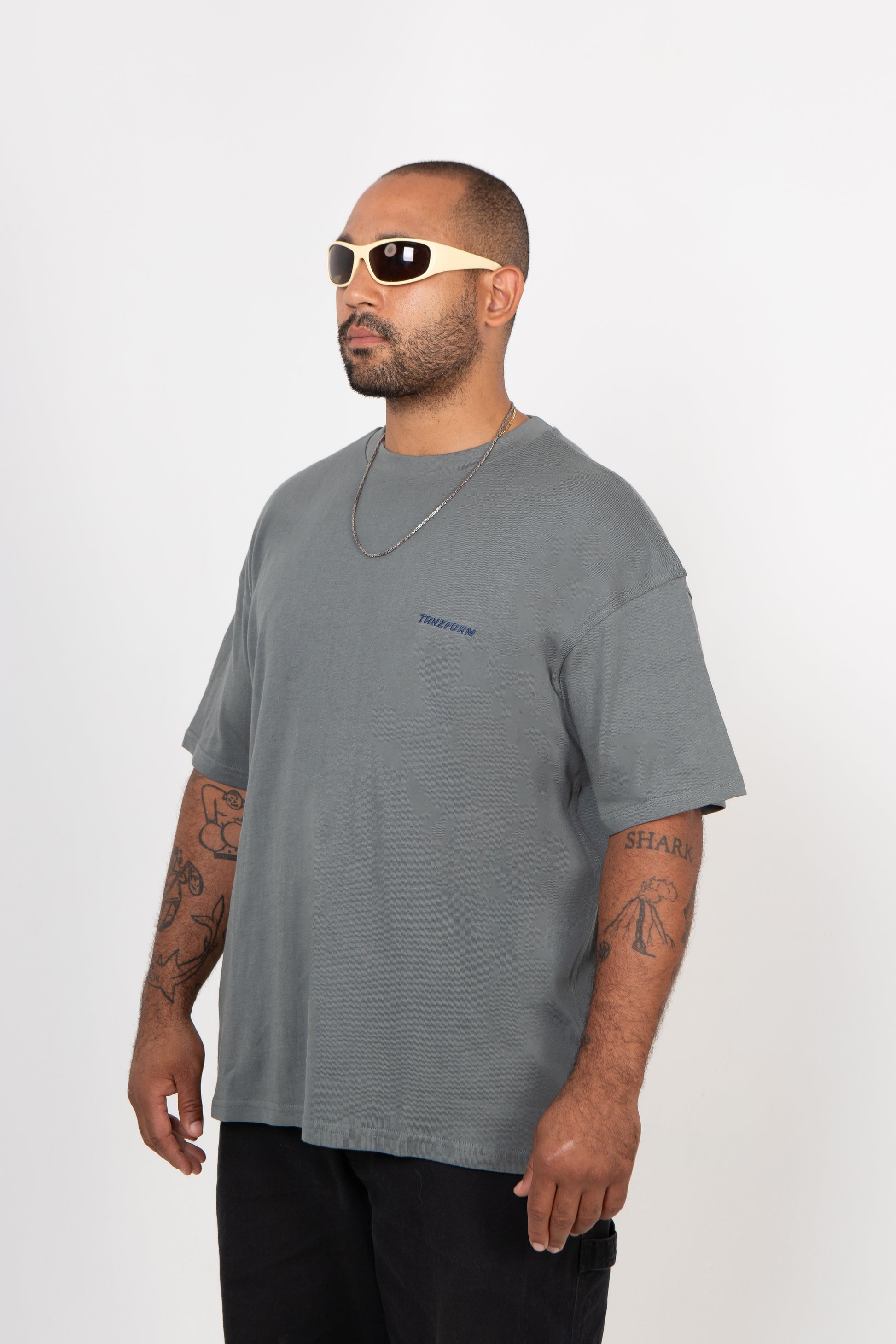 Man wearing a gray t-shirt and sunglasses on a white background