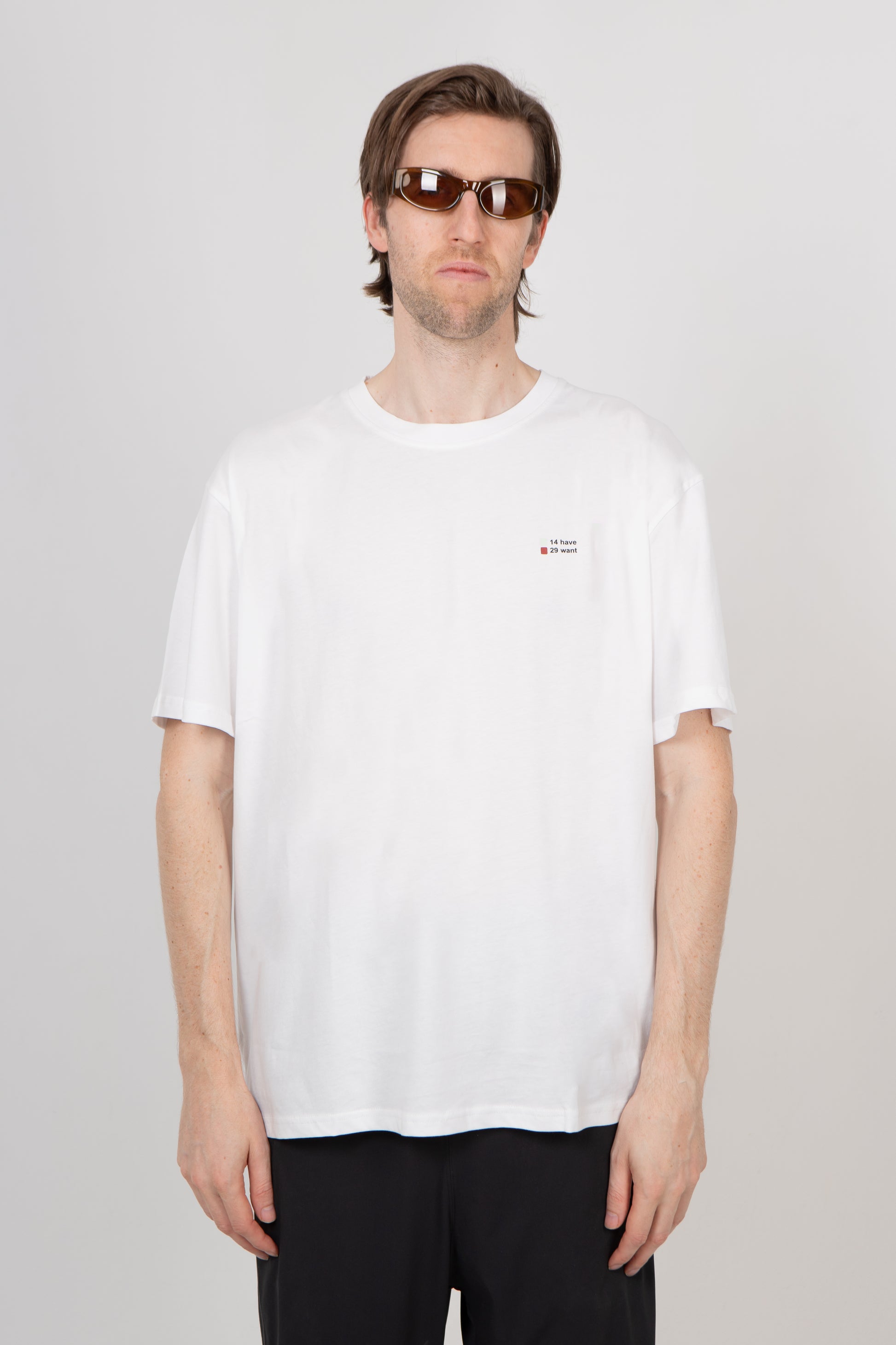 Man wearing a white t-shirt with a small logo on a plain background