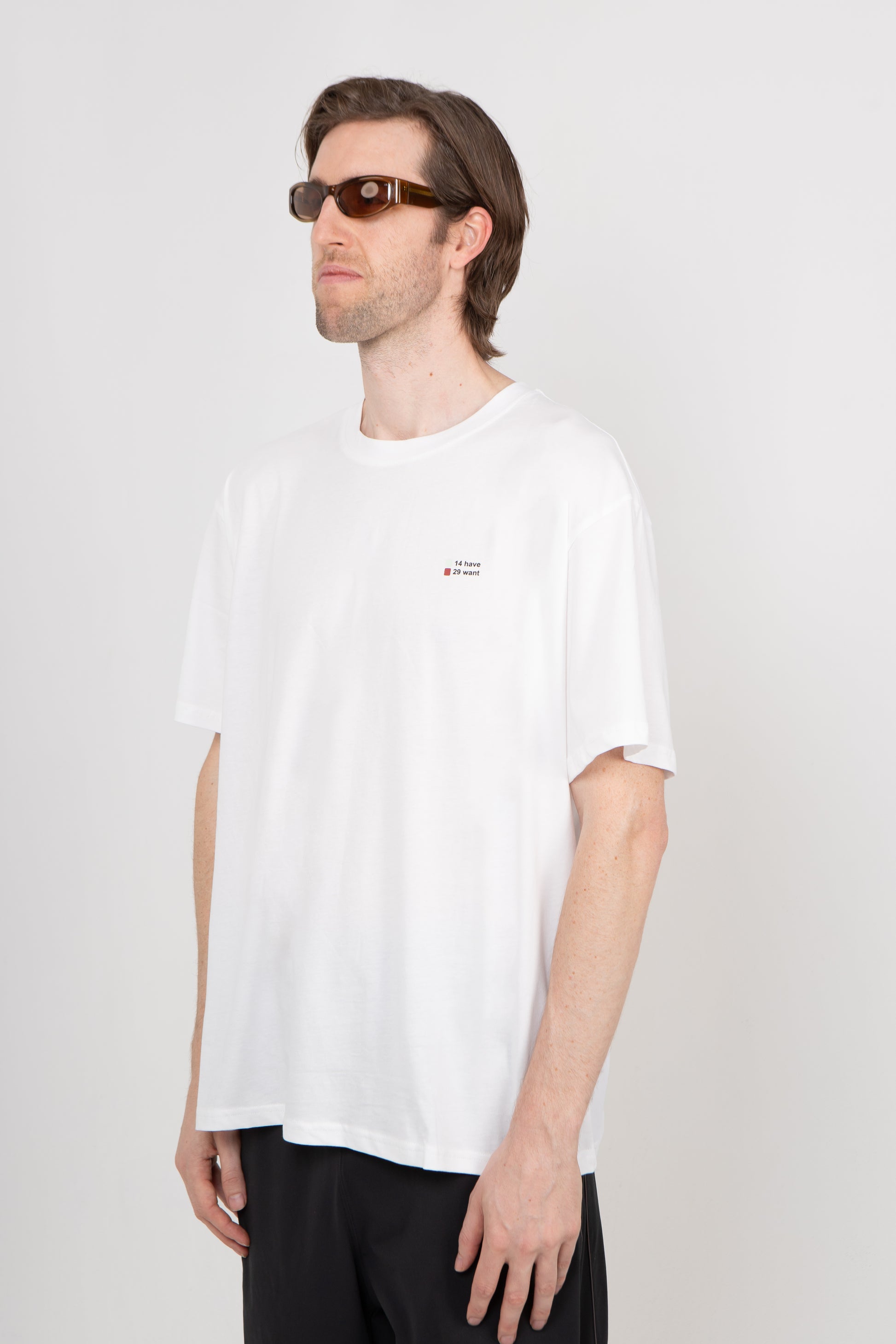 Man wearing a white t-shirt with a small logo on a plain background