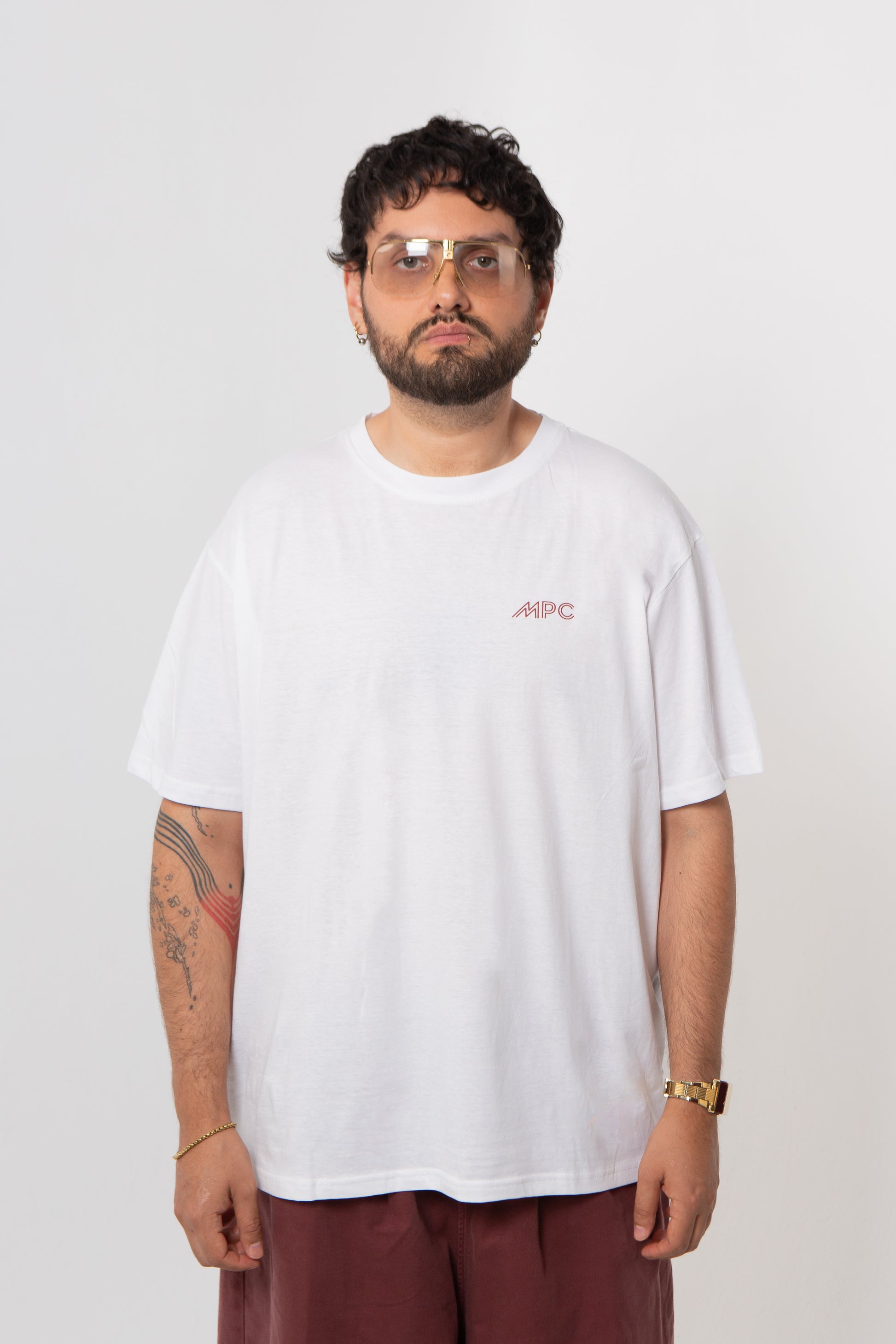 Person wearing a white t-shirt with a logo on a plain background