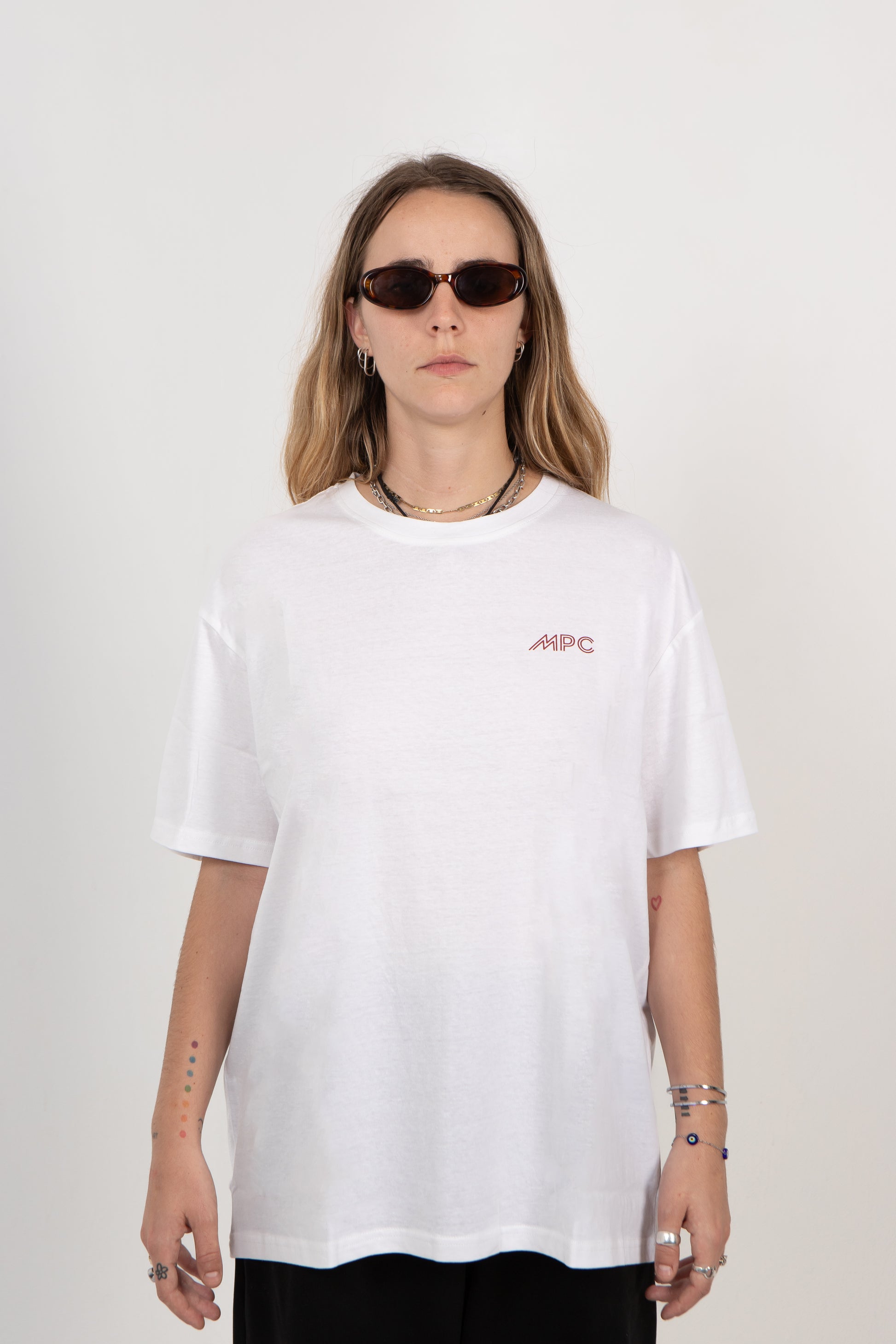 Person wearing a white t-shirt with a logo on a plain background