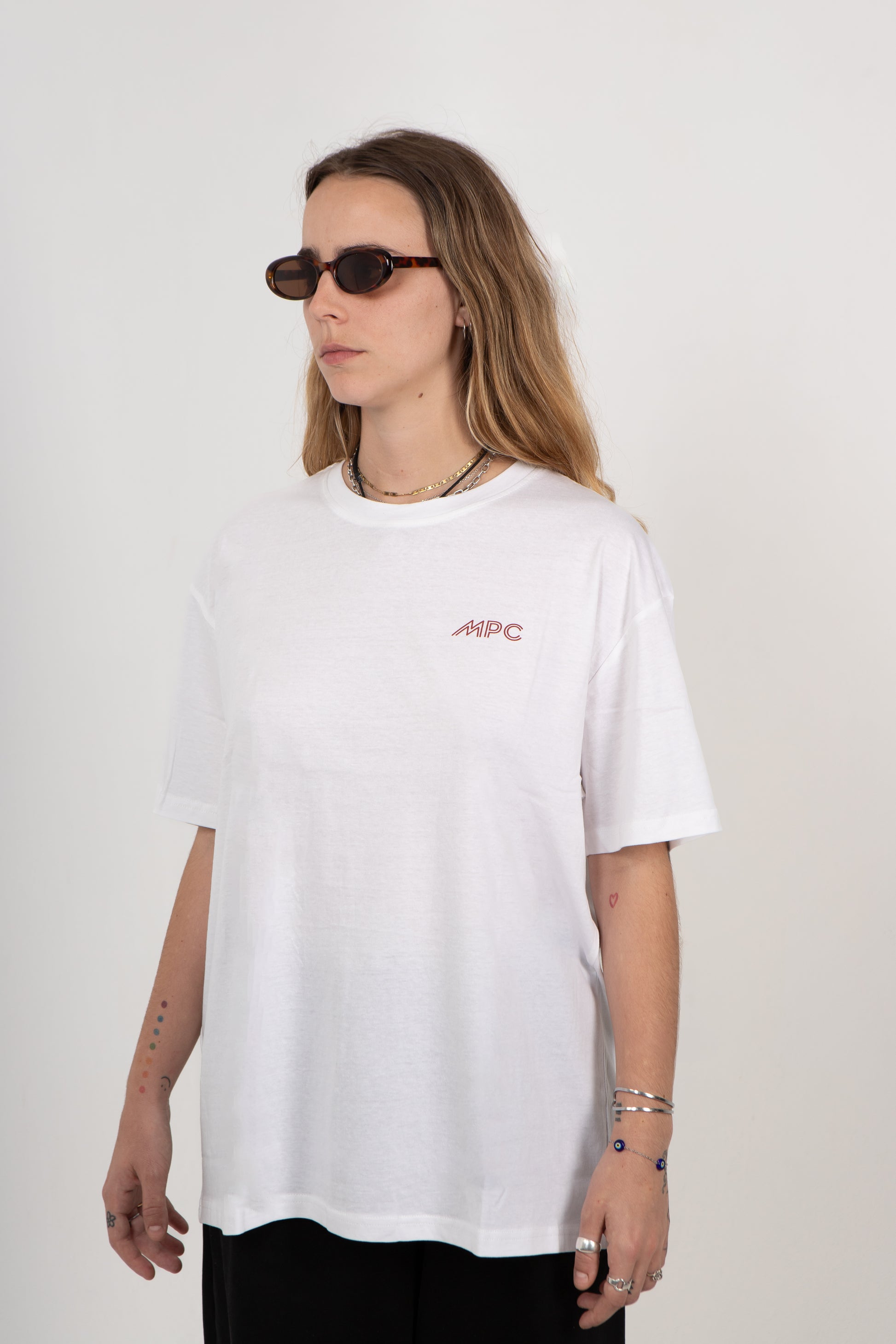 Person wearing a white t-shirt with a logo on a plain background