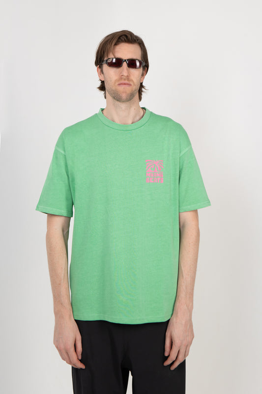 Person wearing a green t-shirt with a small pink logo on a white background