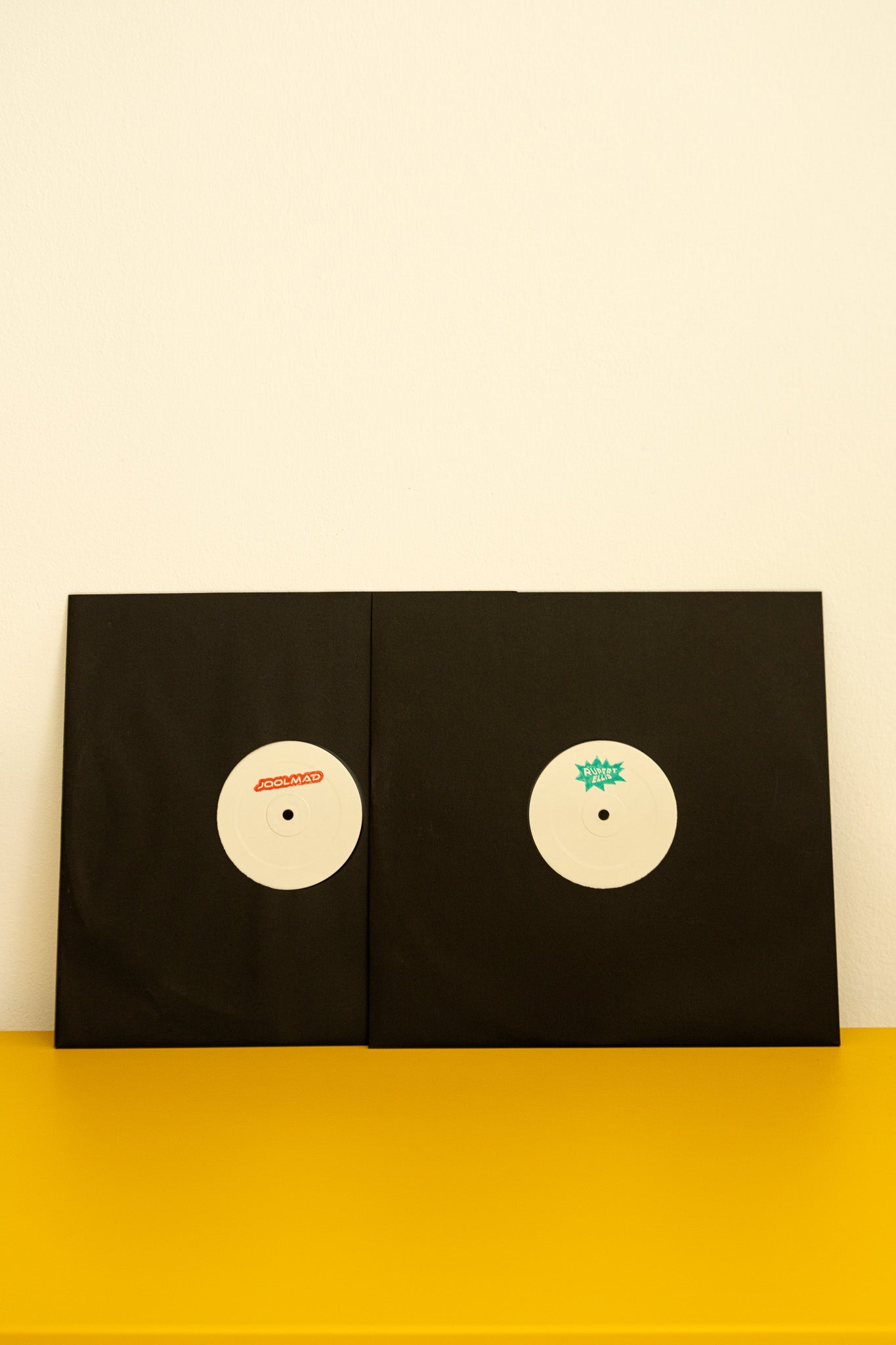 Two black envelopes with circular designs on a yellow surface and beige background