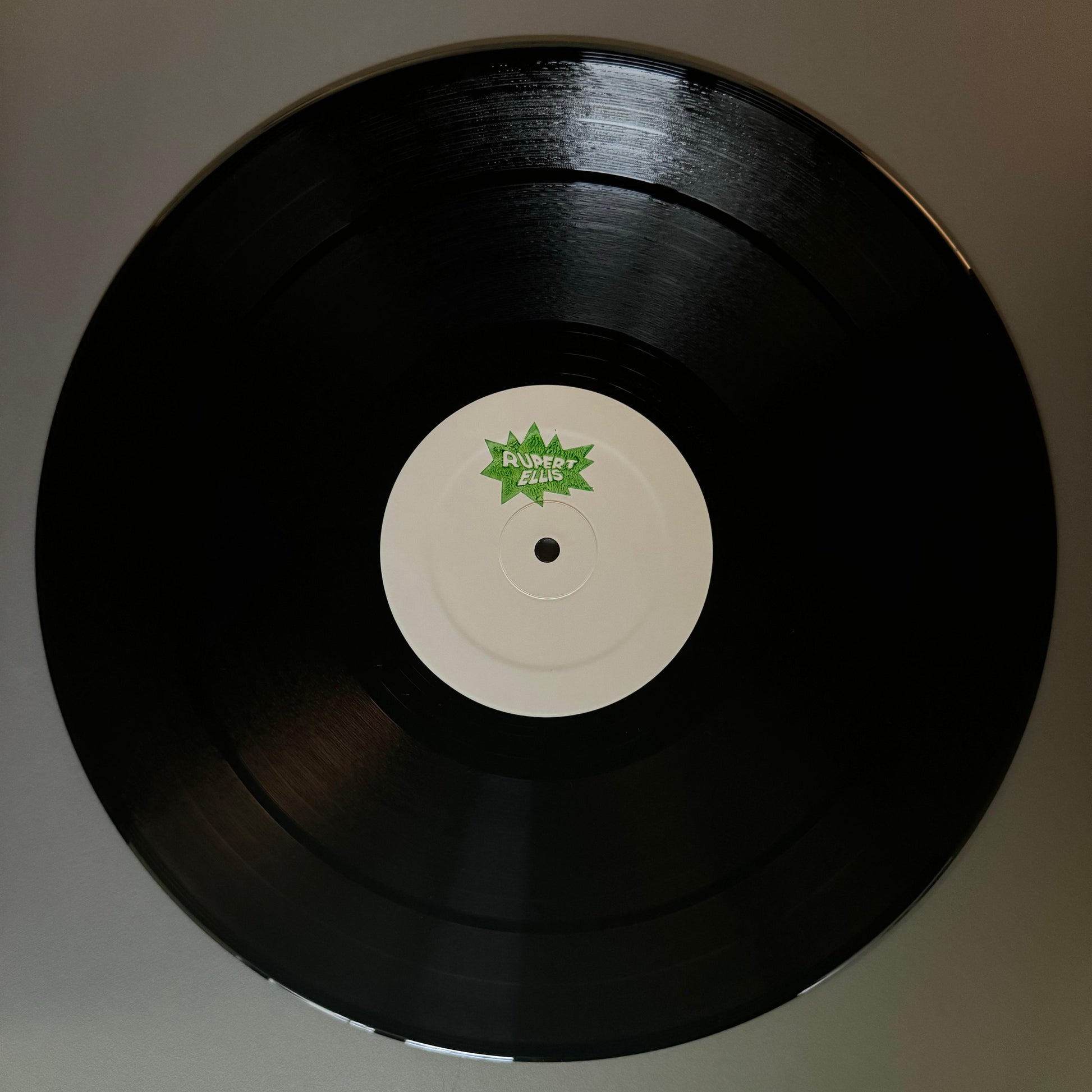 A black vinyl record with a label featuring the text 'STAMPO' and a green leaf logo in the center.