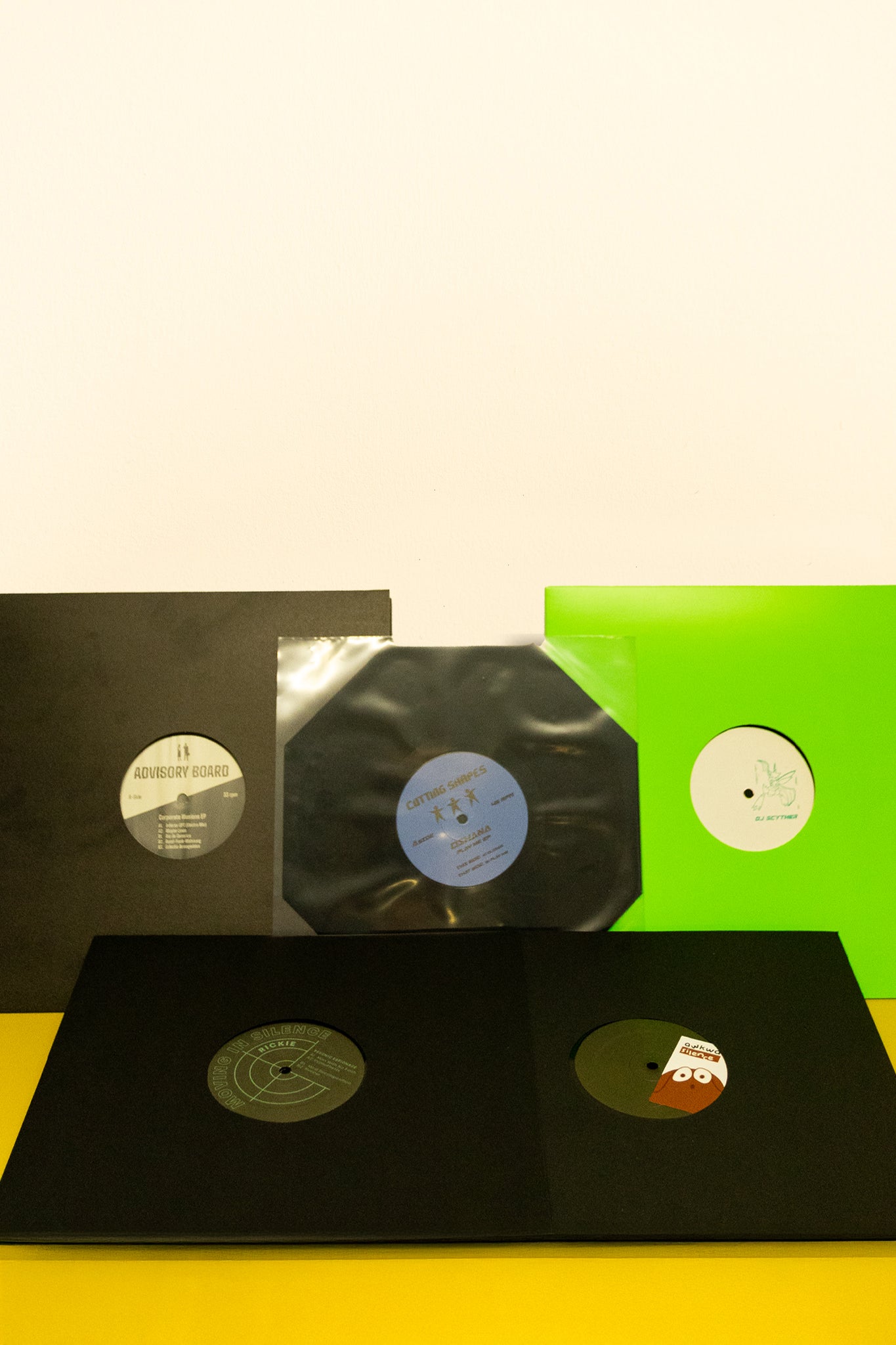 Vinyl records with covers on a yellow surface