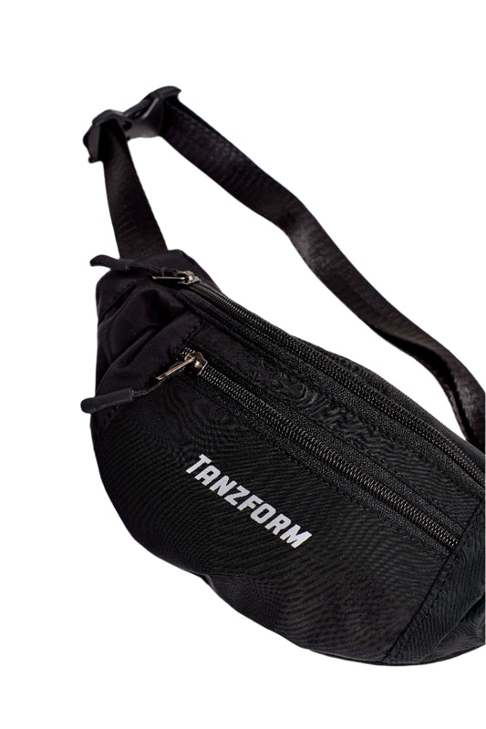 A black cotton bum bag with an adjustable strap and multiple pockets, featuring the text 'TANZFORM' on the side.