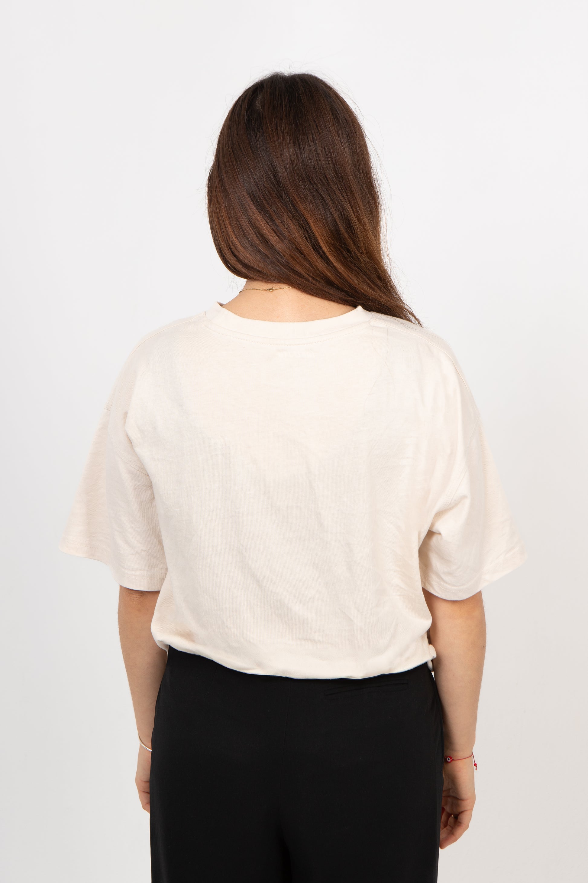 Person wearing a beige top and black pants on a white background