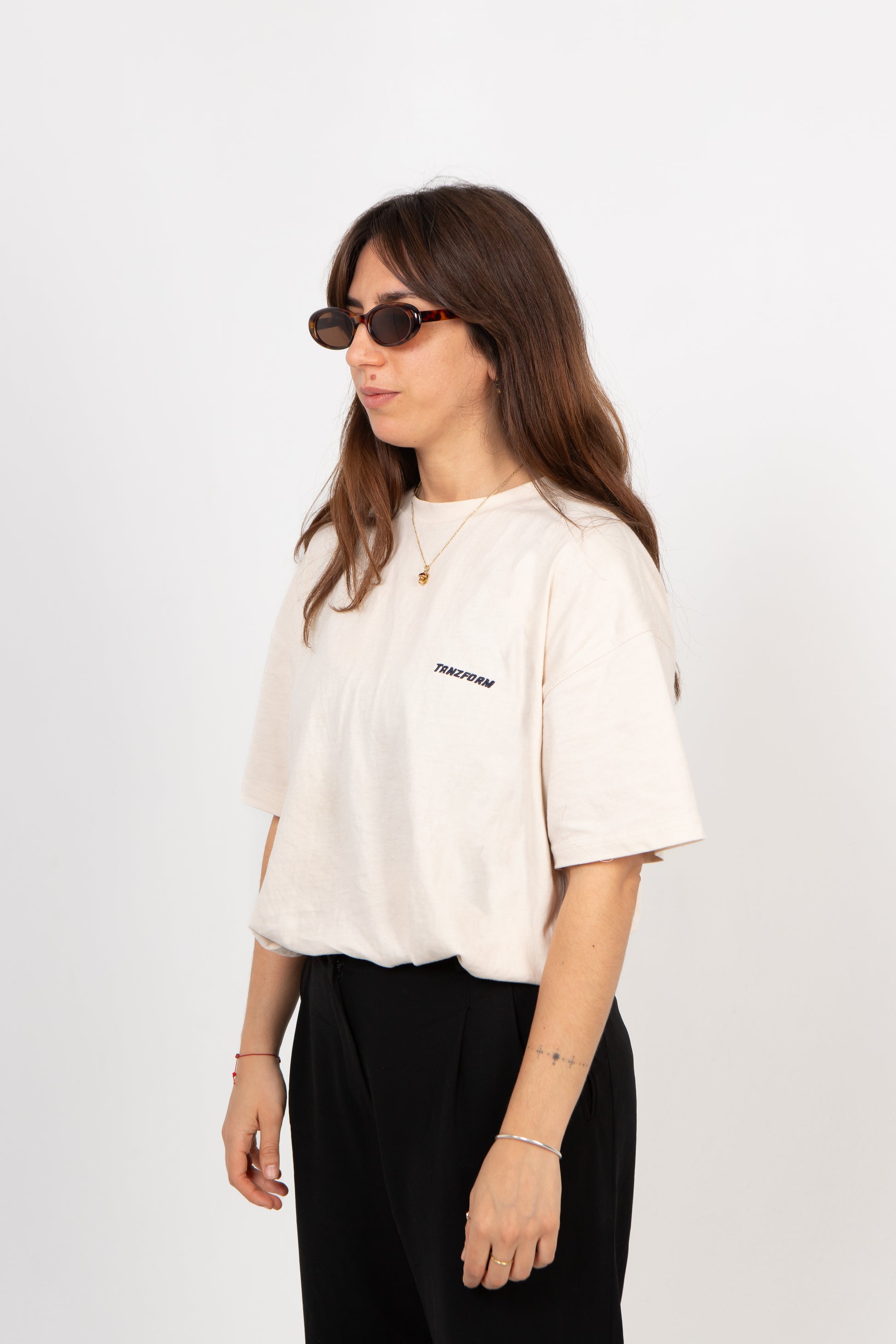 Woman wearing a white t-shirt with a logo on a plain background