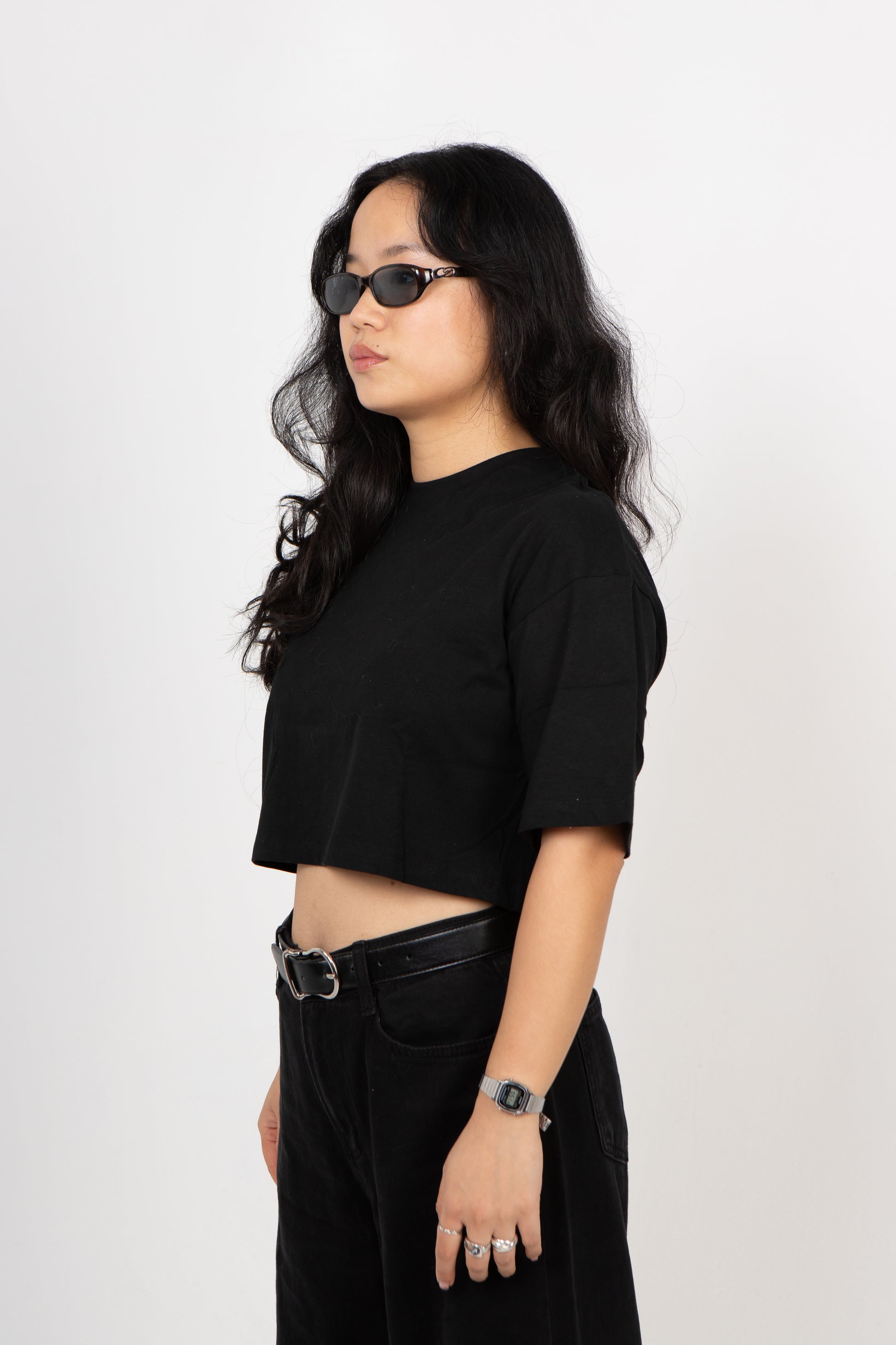 Woman wearing a black outfit with sunglasses on a white background