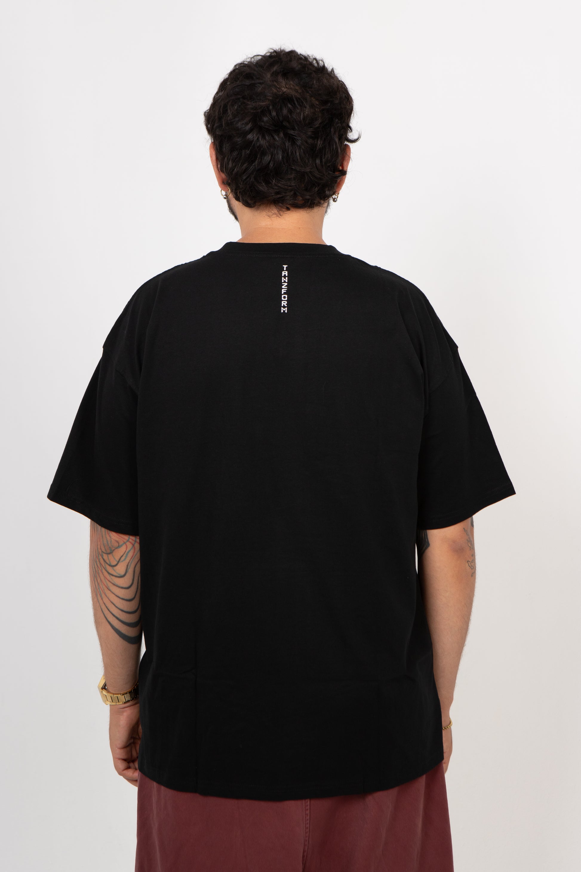 Person wearing a black t-shirt with text on the back against a white background