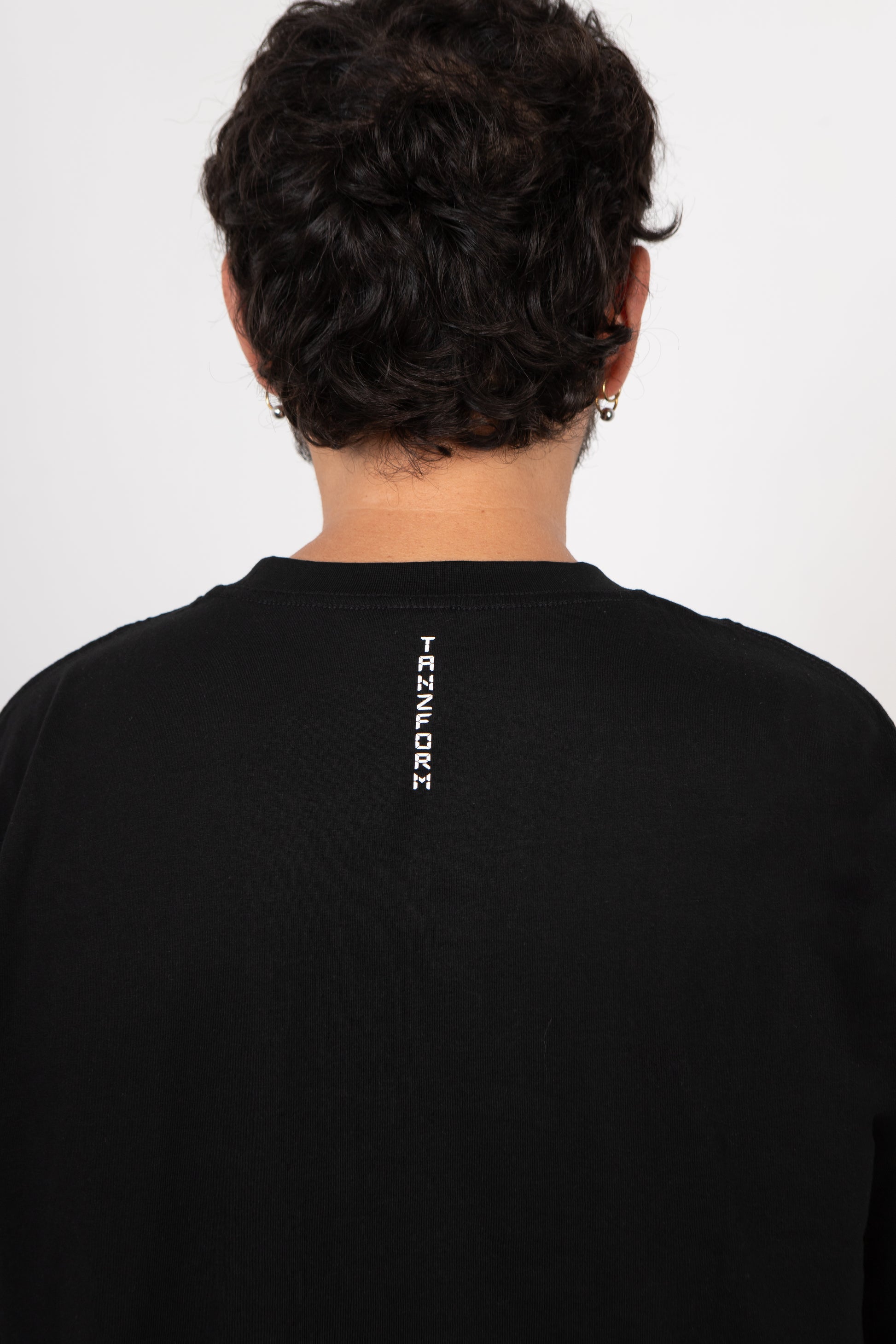 Person wearing a black sweatshirt with 'Transform' logo on the back against a white background
