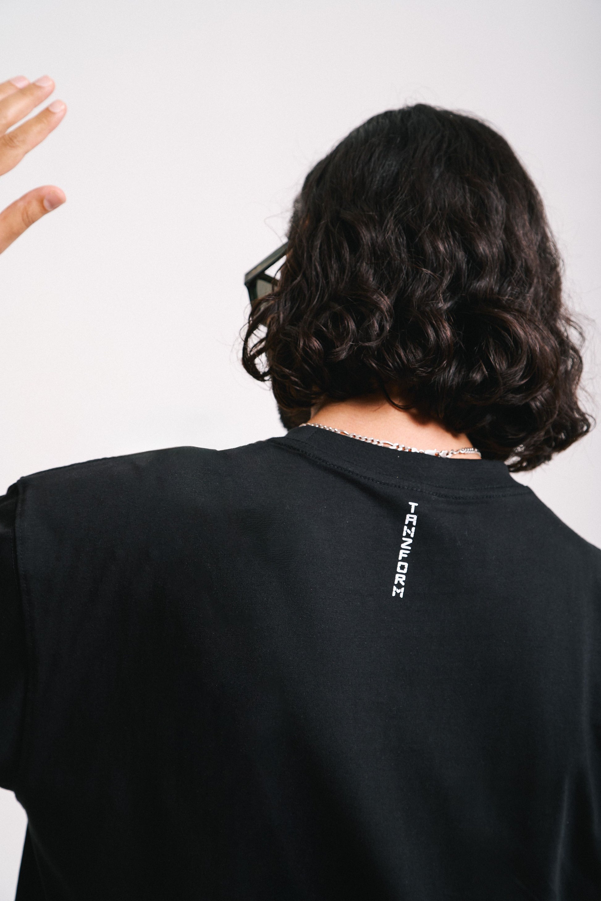 A person wearing a black t-shirt with a white neck print that reads 'Tanzform'.
