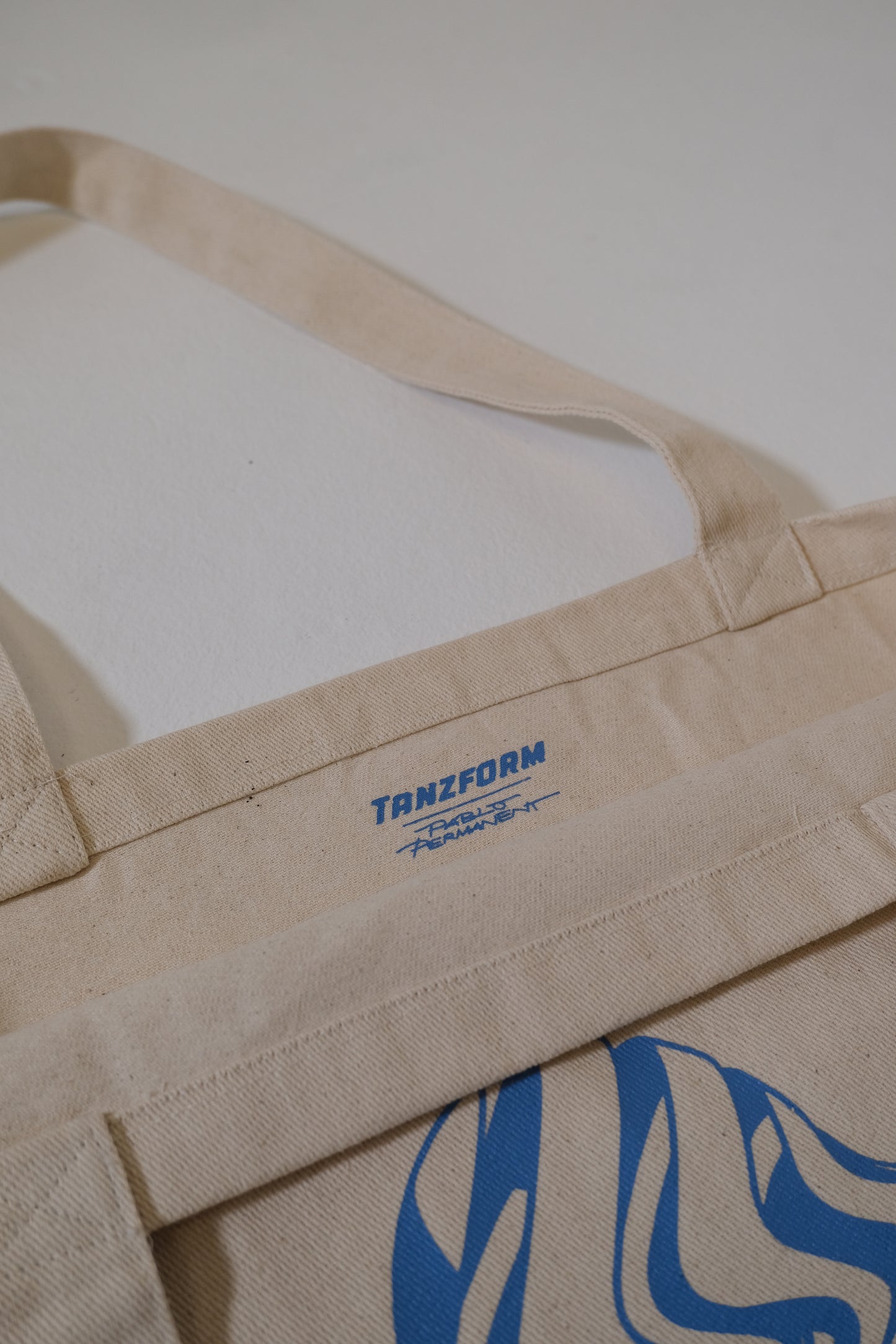 Beige apron with blue logo and text on a white background