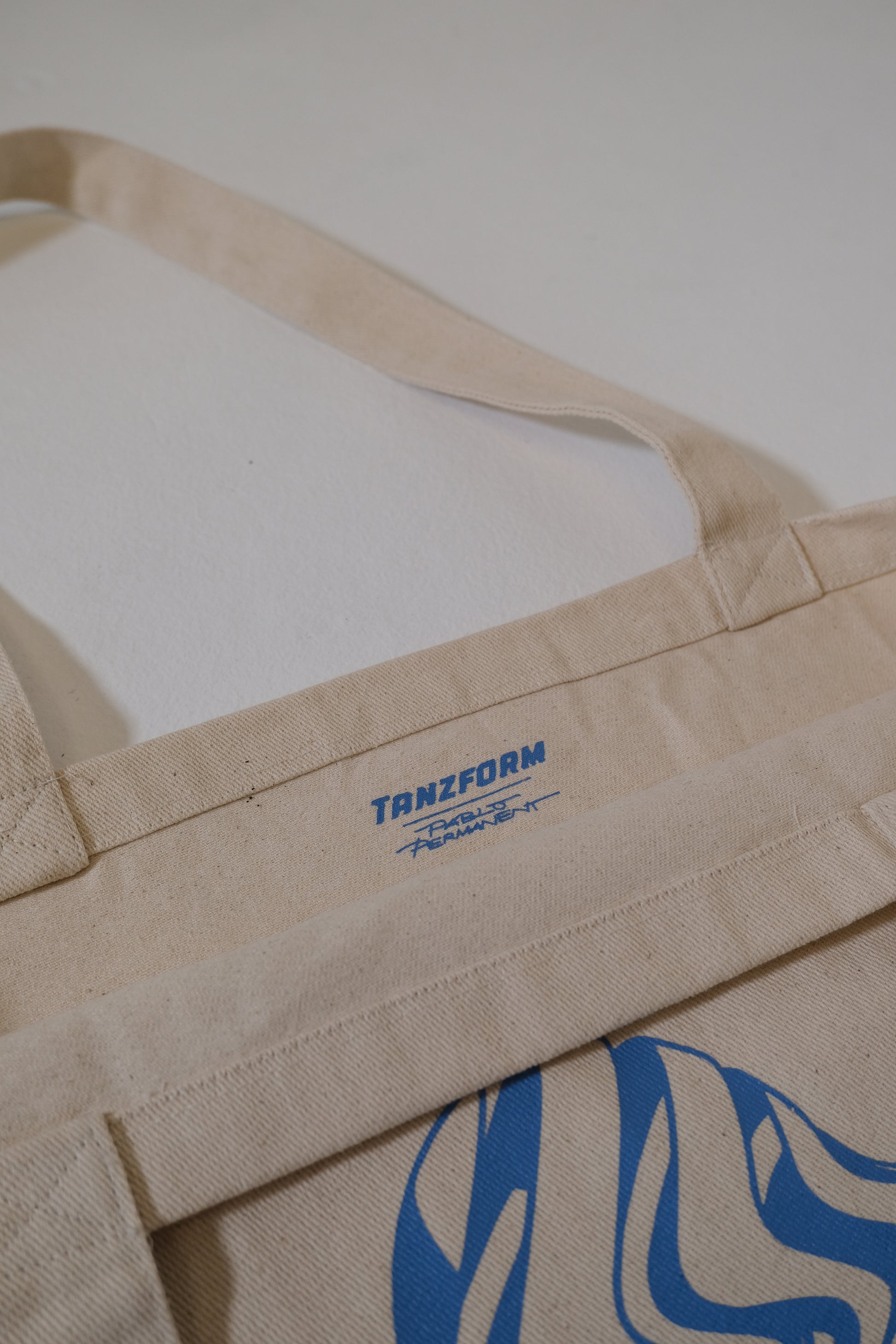 Beige apron with blue logo and text on a white background