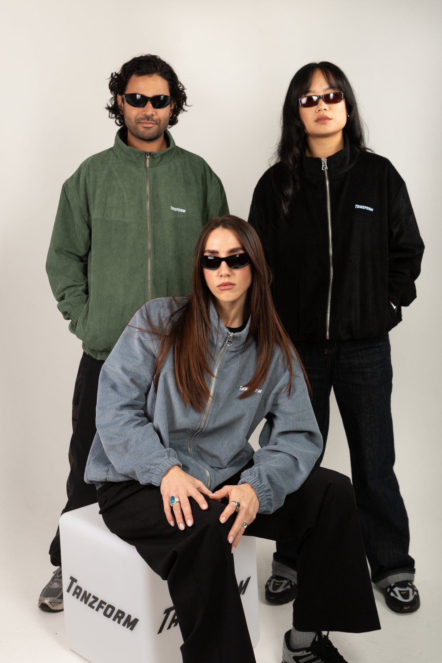 Three people wearing jackets with a visible brand logo on a white background