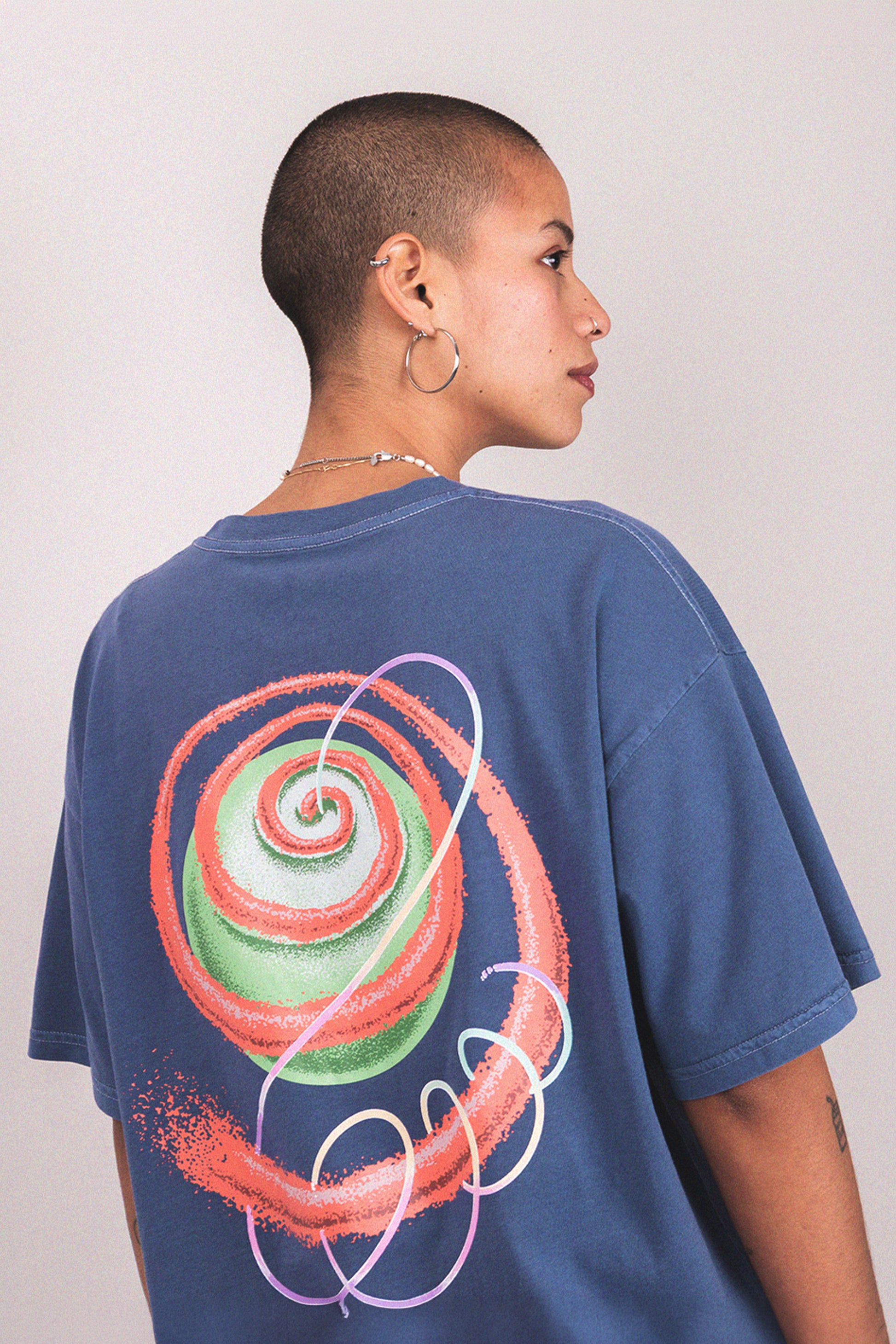 Person wearing a blue trippy t-shirt with a colorful spiral design on the back 