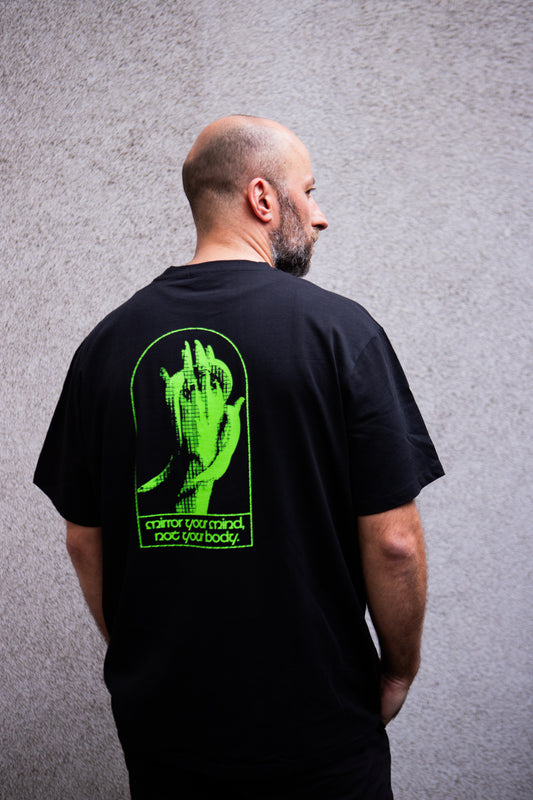 Man wearing a black t-shirt with a green graphic on the back against a gray background