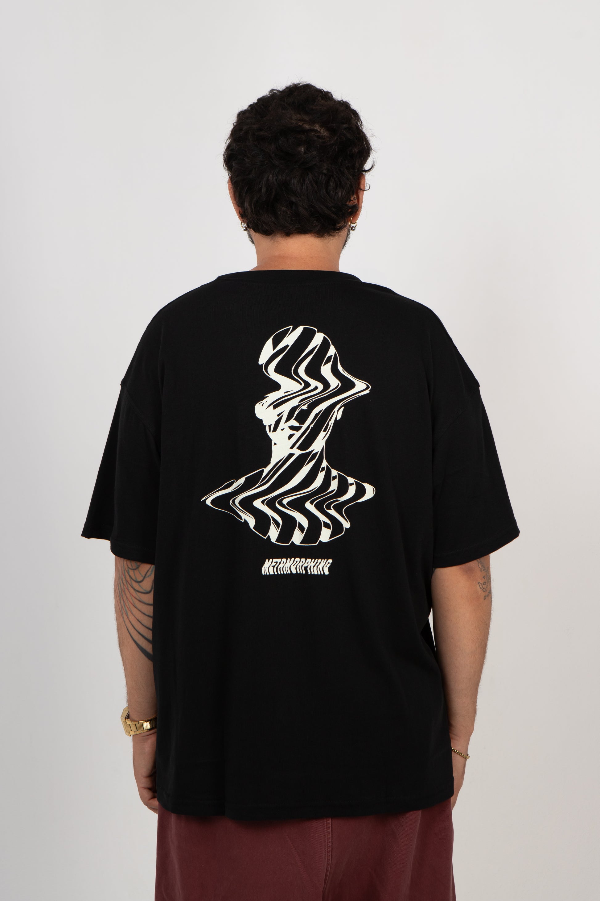 Person wearing a black t-shirt with a white graphic design on the back against a plain background