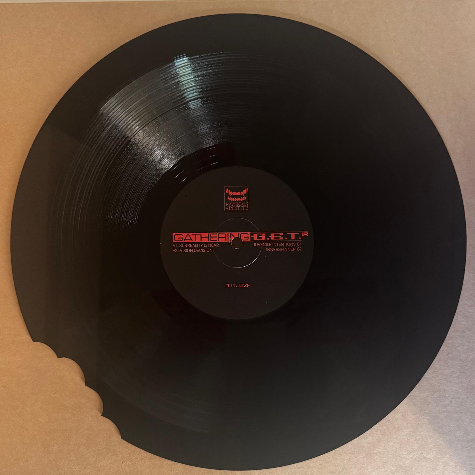 Black vinyl record with a bite out, red label on a cardboard surface