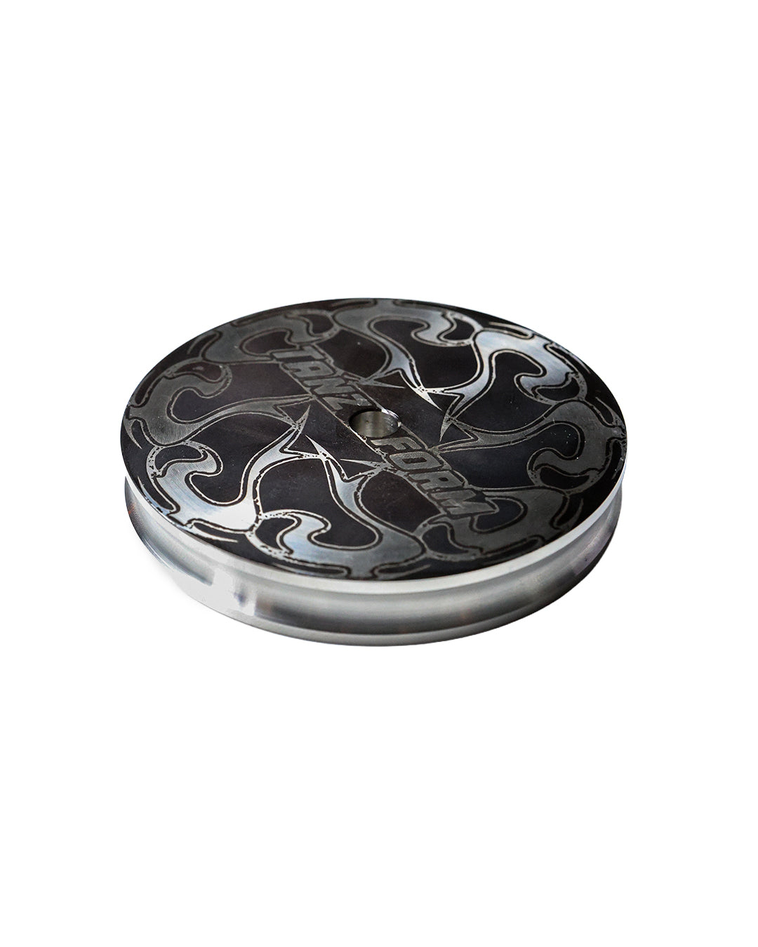 Round metal object used as vinyl weight with black and silver design on a white background