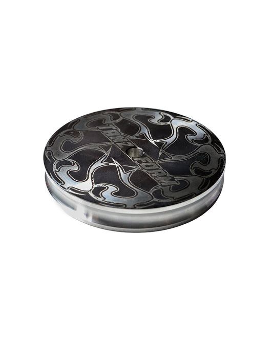Round metal object used as vinyl weight with black and silver design on a white background